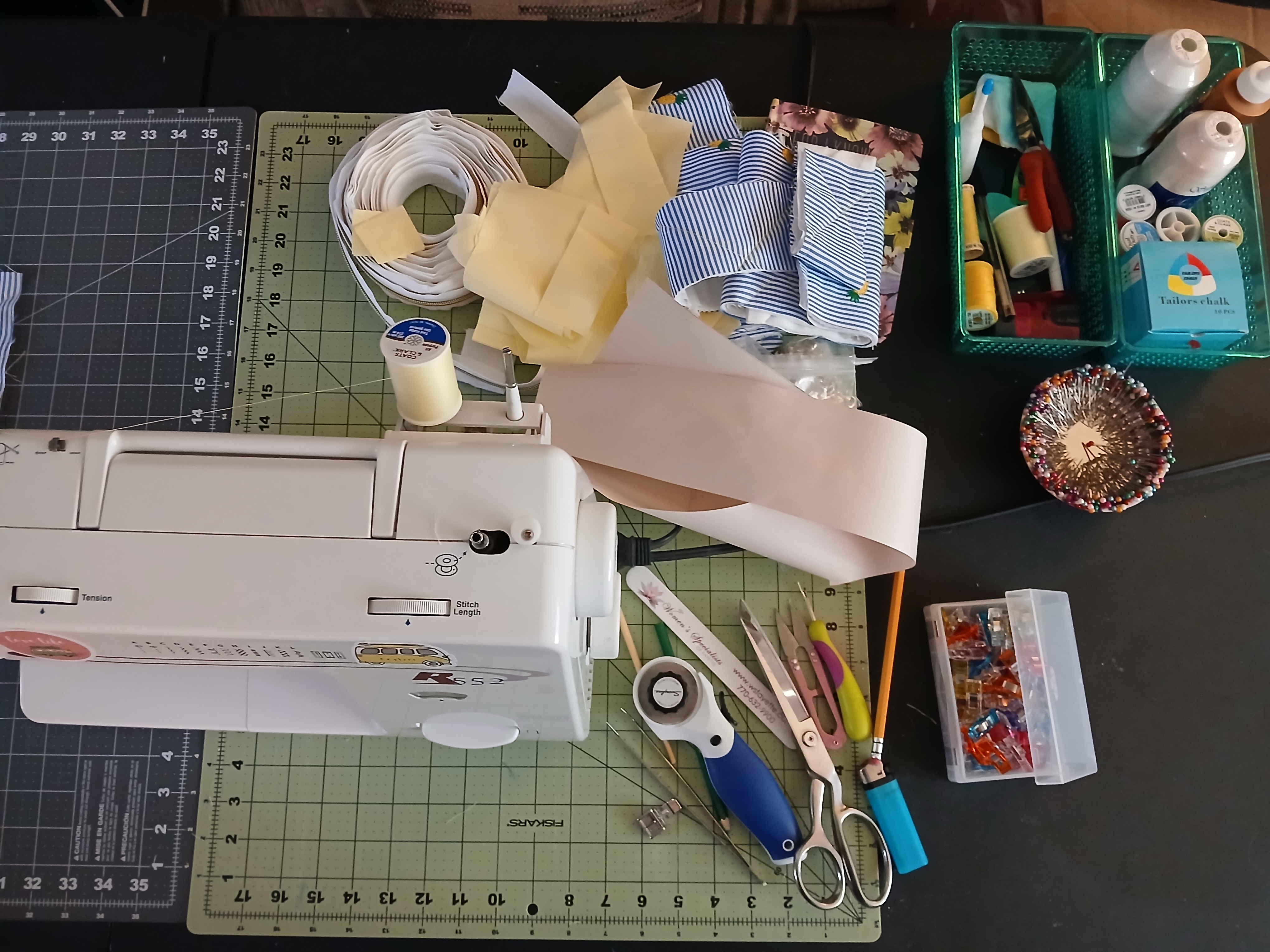 Sewing machine, scissors, thread, and cutting mat on a craft desk